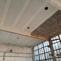 Termool - Poddasze z częściowo nałożoną pianką PUR, widoczne elementy konstrukcyjne i okna. Fragment rusztowania w prawym górnym rogu. Oświetlenie naturalne.