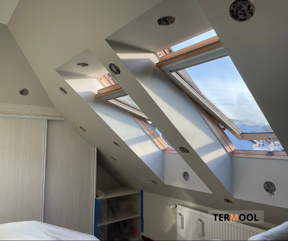 Poddasze w Polkowicach z oknami dachowymi przed montażem oświetlenia, widoczne otwory na oprawy, ściany przygotowane do dalszych prac wykończeniowych.