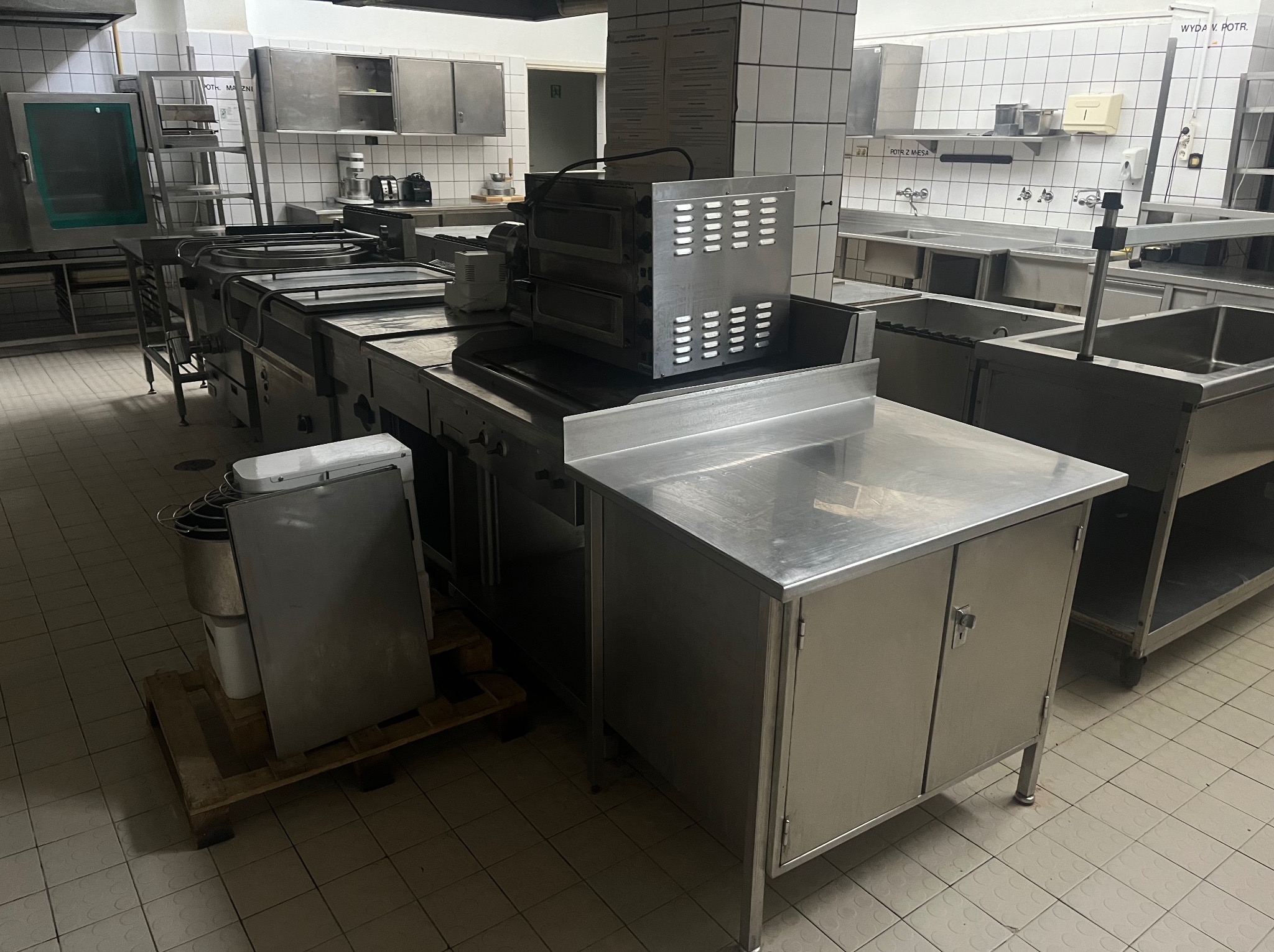 Profesjonalna kuchnia przemysłowa w Kielcach z nierdzewnymi szafkami, stołami roboczymi i piecem, przygotowana do czyszczenia przemysłowego.