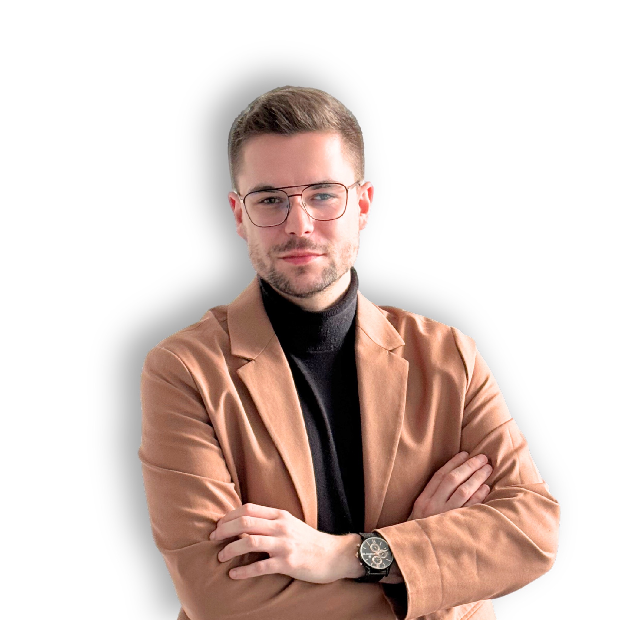 Portret mężczyzny w okularach, czarnym golfie i brązowej marynarce, z założonymi rękami na białym tle.