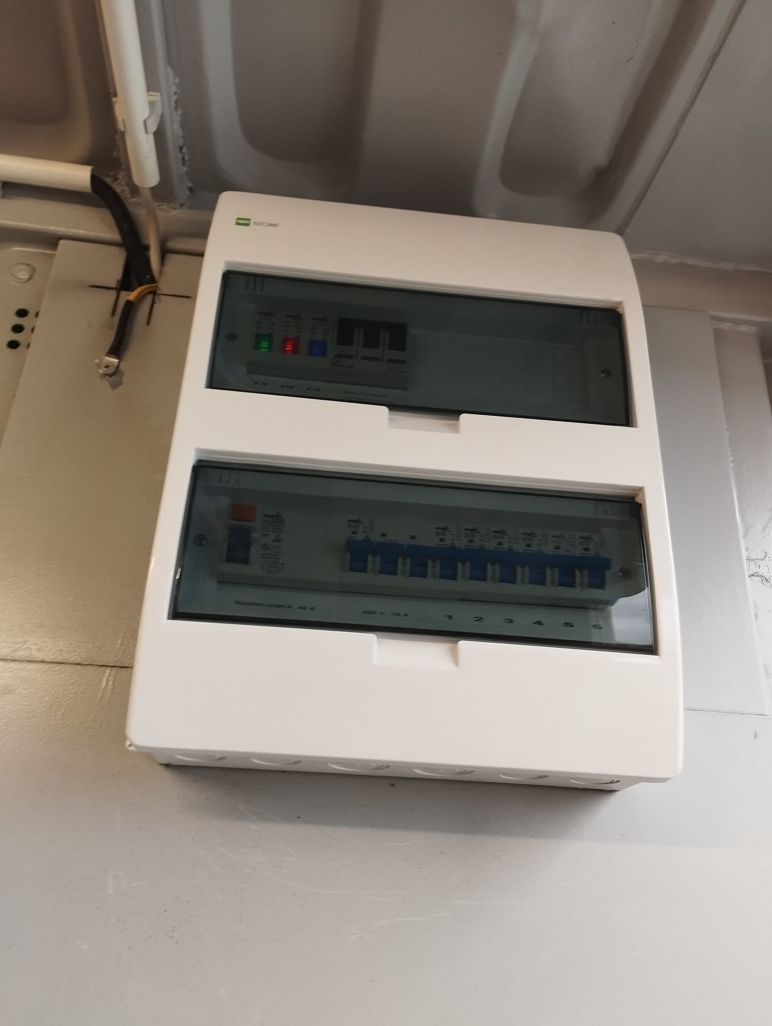 Rozdzielnica elektryczna z bezpiecznikami zamontowana na ścianie w Jelcz-Laskowice, widoczne zabezpieczenia różnicowoprądowe i nadprądowe.