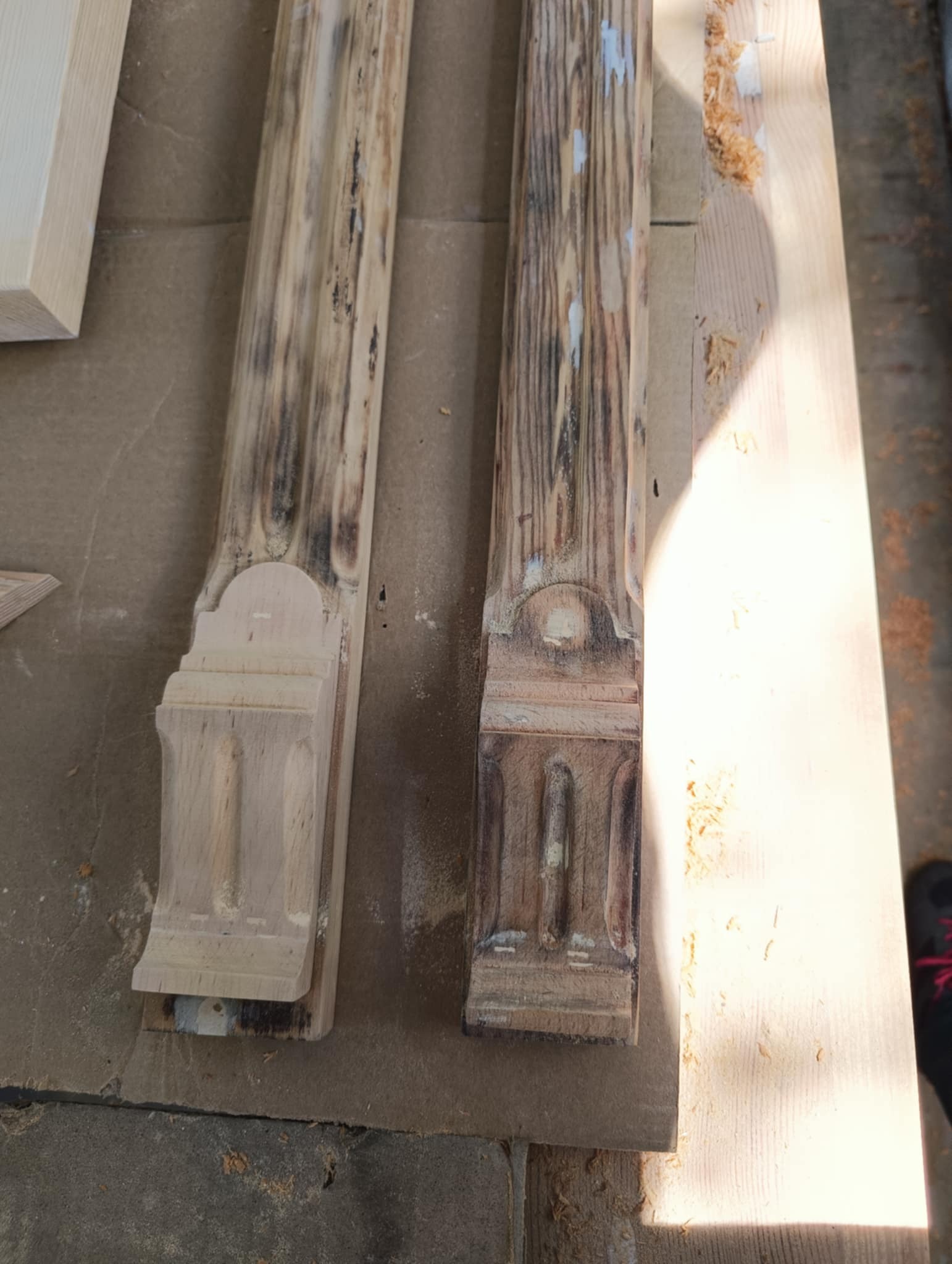 Dwie drewniane kolumny z dekoracyjnymi detalami, jedna oczyszczona, druga z widocznymi śladami zabrudzeń i starej farby, ukazujące postęp prac renowacyjnych.