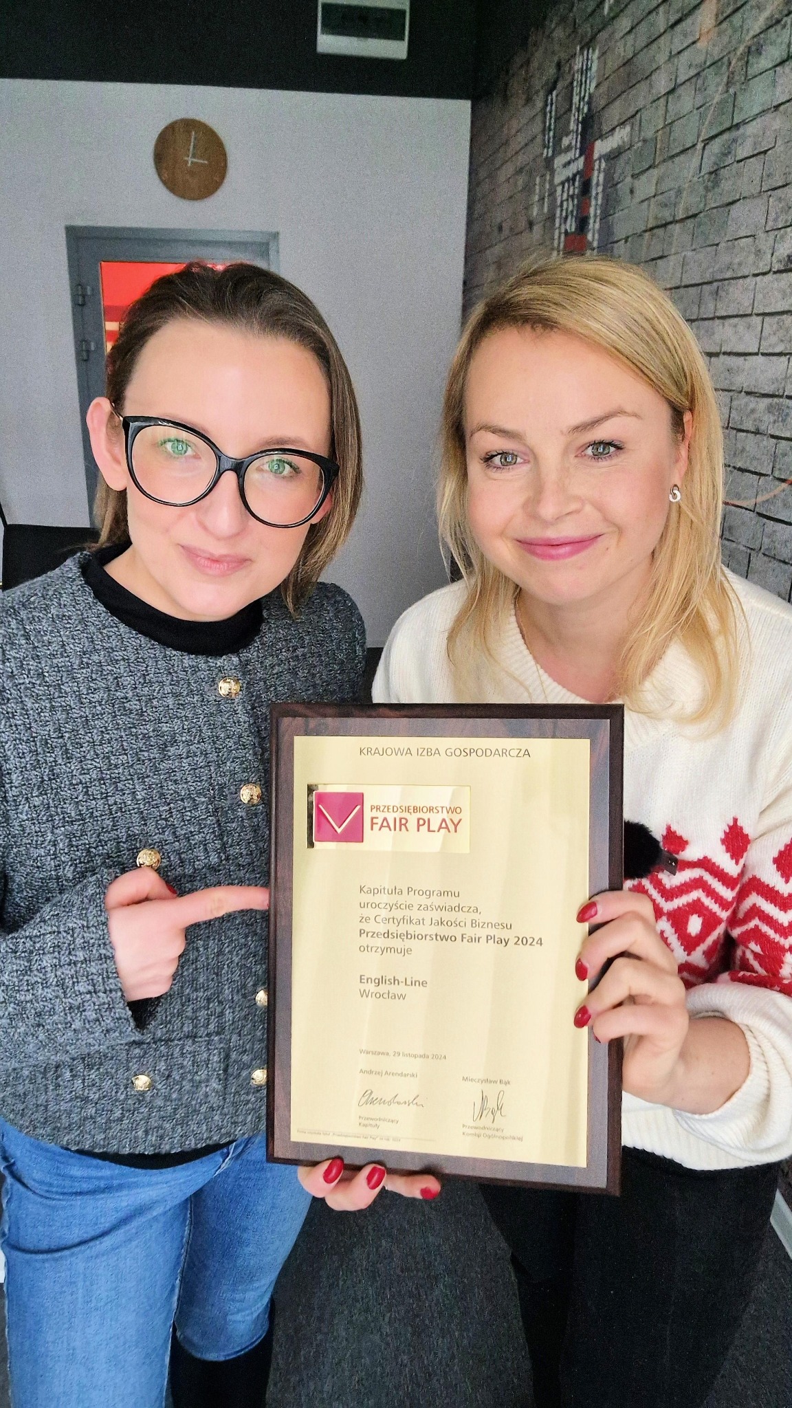 Dwie uśmiechnięte kobiety prezentują certyfikat 'Przedsiębiorstwo Fair Play 2024' dla 'English-Line Wrocław', trzymany w drewnianej ramce.