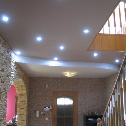 F.H.MIKA MONIKA ZDANCEWICZ - Aranżacja przedpokoju z podwieszanym sufitem z oświetleniem punktowym, kamienną dekoracją łukowego przejścia i drewnianymi schodami z metalowymi balustradami.