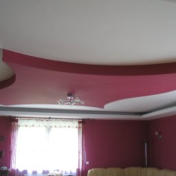 F.H.MIKA MONIKA ZDANCEWICZ - Czerwony, asymetryczny sufit podwieszany z oświetleniem punktowym w pokoju z bordowymi ścianami i jasnym oknem.