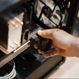 Podłączenie kabla zasilającego do karty graficznej wewnątrz obudowy komputera stacjonarnego. Widoczny radiator i białe kable. Ujęcie z bliska, jasne światło.