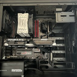 P-cet - Wnętrze obudowy komputera stacjonarnego z kartą graficzną GeForce RTX, chłodzeniem be quiet!, płytą główną MSI i zasilaczem Corsair RM1000e. Widoczne kable i komponenty.