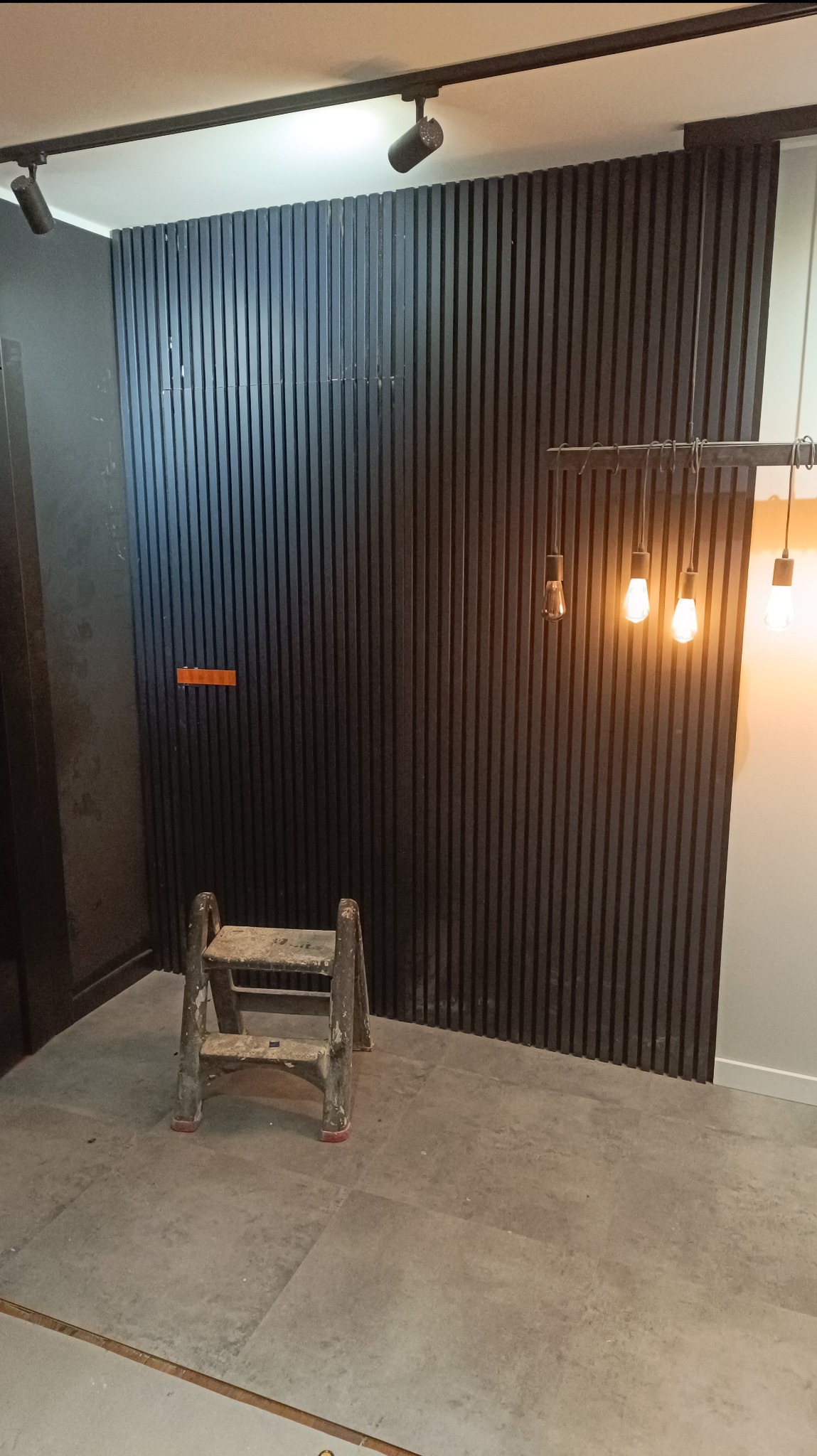 Montaż dekoracyjnych paneli ściennych w Brzeżnie, widoczna drabina malarska i oświetlenie sufitowe.