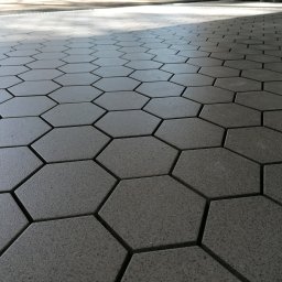 EST-BUD - Szara, sześciokątna kostka brukowa ułożona na powierzchni, widok z niskiej perspektywy z lekkim cieniem u góry.