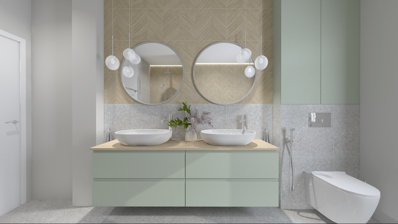 Nowoczesna łazienka z dwoma okrągłymi lustrami, podwójną umywalką nablatową na szafce w pastelowym zielonym kolorze, wiszącą toaletą i subtelnym oświetleniem w postaci szklanych kul.