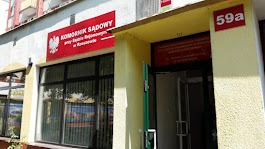 Wejście do budynku z szyldem 'Komornik Sądowy przy Sądzie Rejonowym w Krakowie', numer budynku 59a, widoczne okna i drzwi wejściowe.