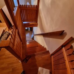 D&D USŁUGI REMONTOWO-BUDOWLANE PAWEŁ DUBIEL - Widok z góry na drewniane schody z balustradą w trakcie montażu w domu w Gryfowie Śląskim, widoczne niedokończone elementy i podłoga.