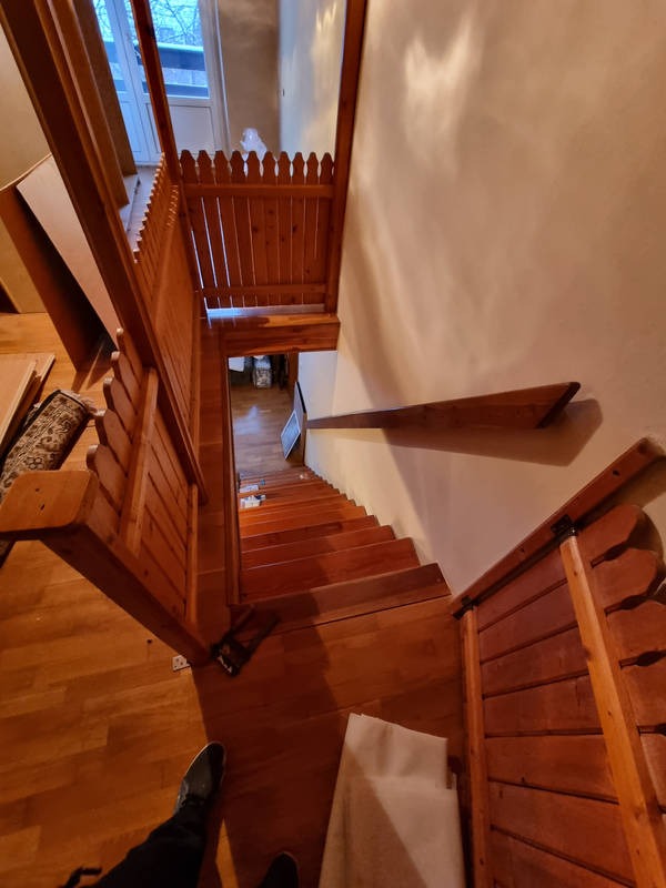 Widok z góry na drewniane schody z balustradą w trakcie montażu w domu w Gryfowie Śląskim, widoczne niedokończone elementy i podłoga.