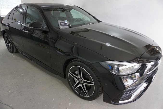 Błyszczący, czarny Mercedes C-klasa po detailingu, z widocznym odbiciem światła na karoserii i ściereczką mikrofibry na masce.