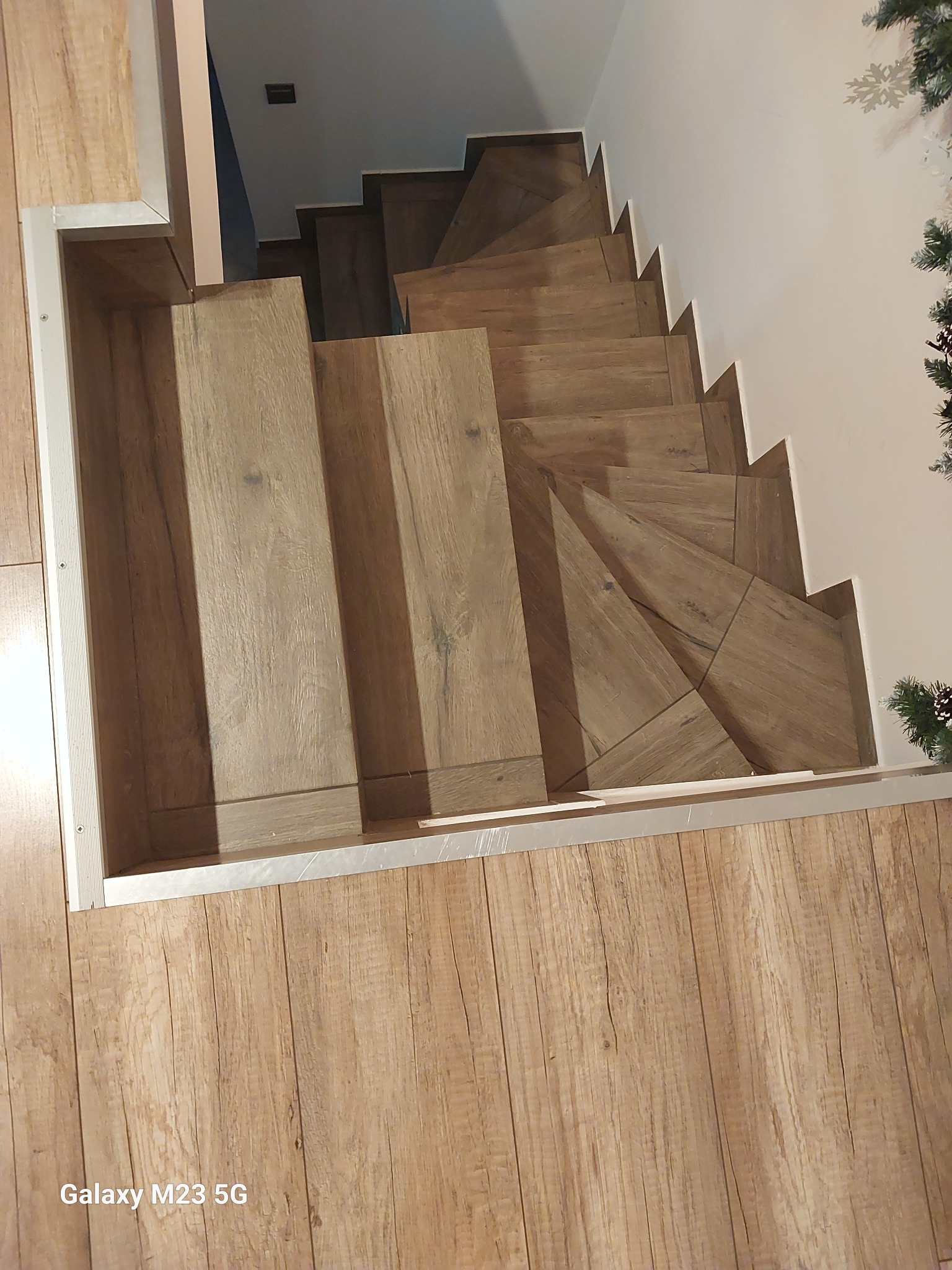 Schody wewnętrzne wykończone panelami imitującymi drewno, widok z góry, z fragmentem dekoracji świątecznej w prawym górnym rogu.