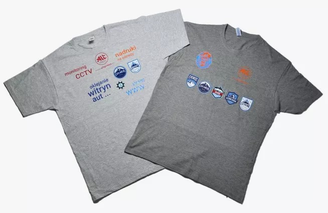 Dwa szare T-shirty z różnymi nadrukami: jeden z logo firmy i hasłami reklamowymi w kolorach czerwonym i niebieskim, drugi z naszywkami górskimi i logo wypraw.