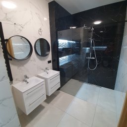 Majsterhome - Nowoczesna łazienka z czarno-białymi marmurkowymi płytkami, dwoma umywalkami z szafkami i okrągłymi lustrami, kabina prysznicowa walk-in.