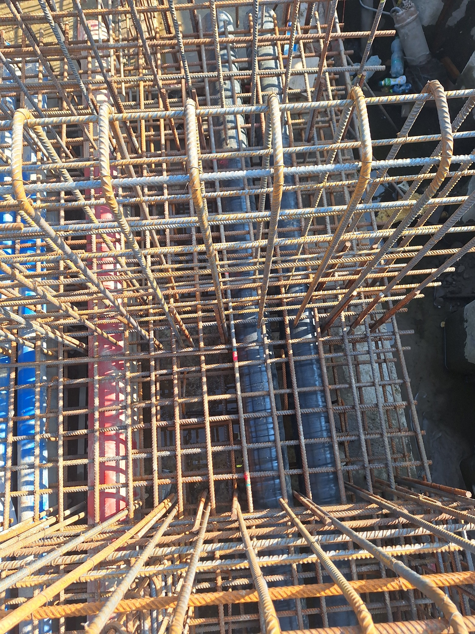 Siatka zbrojeniowa z prętów żebrowanych, widok z góry, z widocznymi rurami instalacyjnymi wewnątrz konstrukcji.