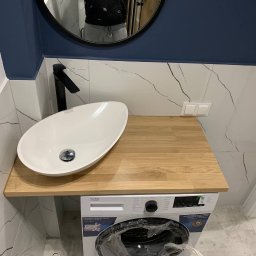 TamamBud - Nowoczesna łazienka z umywalką nablatową o owalnym kształcie i czarną armaturą, zamontowaną na drewnianym blacie nad pralką Beko, białe płytki z szarymi żyłkami na ścianie, widoczne odbicie osoby...