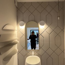 DINAS MASTER DMYTRO OKHRIMENKO - Nowoczesna łazienka z umywalką wolnostojącą, geometrycznymi płytkami na ścianie i podświetlanym lustrem, odbicie osoby robiącej zdjęcie w lustrze.