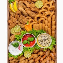 Pudelkowelove - Różnorodne przekąski smażone w głębokim tłuszczu, ułożone w kartonowym pudełku, ozdobione sałatą, plasterkami cytryny i limonki, z trzema miseczkami sosów: czosnkowy, pomidorowy z bazylią i tahini...