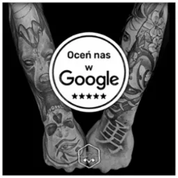 Czarno-białe zdjęcie dwóch wytatuowanych rąk, z grafikami przedstawiającymi egipskie motywy i kwiaty, nałożony okrągły baner z napisem 'Oceń nas w Google' i pięcioma gwiazdkami, w dolnej części...