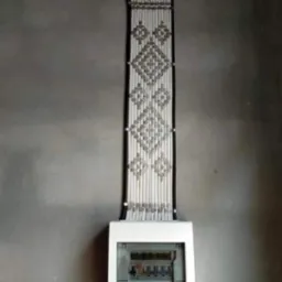 Elegancko ułożone kable elektryczne tworzące wzór na ścianie nad białą skrzynką rozdzielczą. Estetyczna instalacja w surowym wnętrzu.