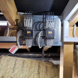 Dwa przełączniki Televes Novoswitch zamontowane na perforowanej płycie, z widocznymi kablami i elementami konstrukcji dachu. Widoczna etykieta Velux.