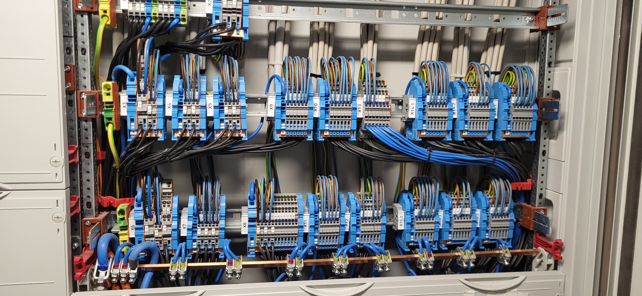 Rozdzielnica elektryczna z precyzyjnie ułożonymi przewodami i listwami zaciskowymi. Widoczne oznaczenia X3, X4, X5, X9, X10, X13, X14.1, X14.2, X15.1, X15.2.