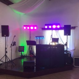 Gajewski Band - Scena z profesjonalnym sprzętem nagłośnieniowym i oświetleniowym gotowa do imprezy, widoczne kolumny Yamaha, reflektory LED w kolorach różowym, zielonym i niebieskim, mikser DJ-ski oraz gitara...