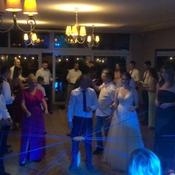 Gajewski Band - Grupa osób uczestniczy w zabawie z niebieskimi sznurkami podczas uroczystości w sali z żyrandolami.