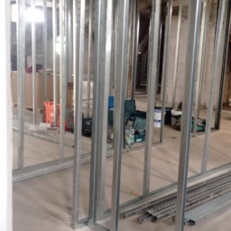 Usługi budowlane Vladysław Kliatskyi - Konstrukcja szkieletowa ścian działowych z profili stalowych w trakcie montażu, widoczne narzędzia i materiały budowlane w tle.