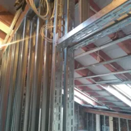 Konstrukcja szkieletowa z profili stalowych pod płyty karton-gips na poddaszu, widoczne przewody elektryczne i drewniany szkielet dachu.