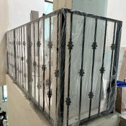 Spawpodklucz - Nowa balustrada metalowa z dekoracyjnymi elementami, zabezpieczona folią ochronną na schodach w trakcie prac wykończeniowych.