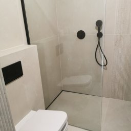 Artur Czuchrak - Nowoczesna łazienka z kabiną typu walk-in, armaturą w kolorze czarnym i podwieszaną toaletą. Minimalistyczny design z płytkami w odcieniach beżu i szarości.