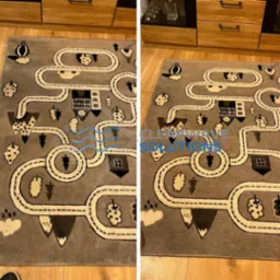 Dwa ujęcia tego samego szarego dywanu dziecięcego z motywem miasteczka i dróg, widoczne ślady użytkowania przed czyszczeniem po lewej, a po prawej zamazane logo firmy czyszczącej.