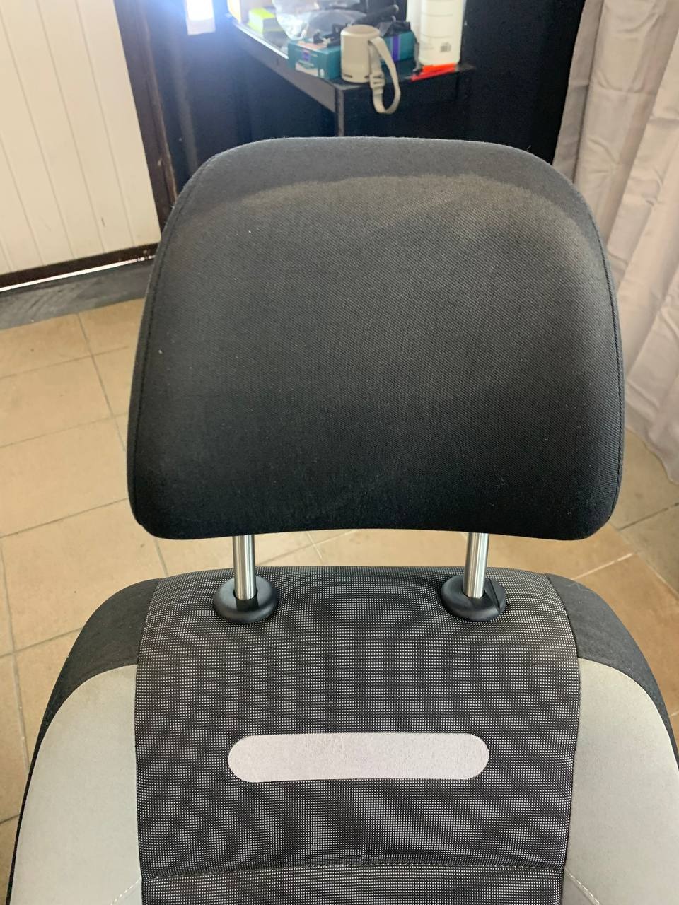 Część fotela samochodowego z widocznym śladem po czyszczeniu na zagłówku z ciemnej tapicerki.