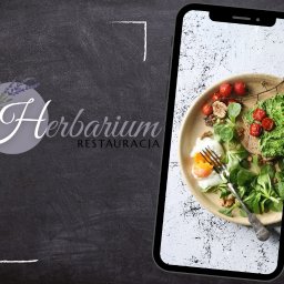 Restauracja Herbarium - Zdjęcie talerza z jajkiem sadzonym, kanapką z zieloną pastą i pomidorami koktajlowymi, orzechami i sałatą, prezentowane na ekranie smartfona, obok logo restauracji Herbarium na ciemnym tle.