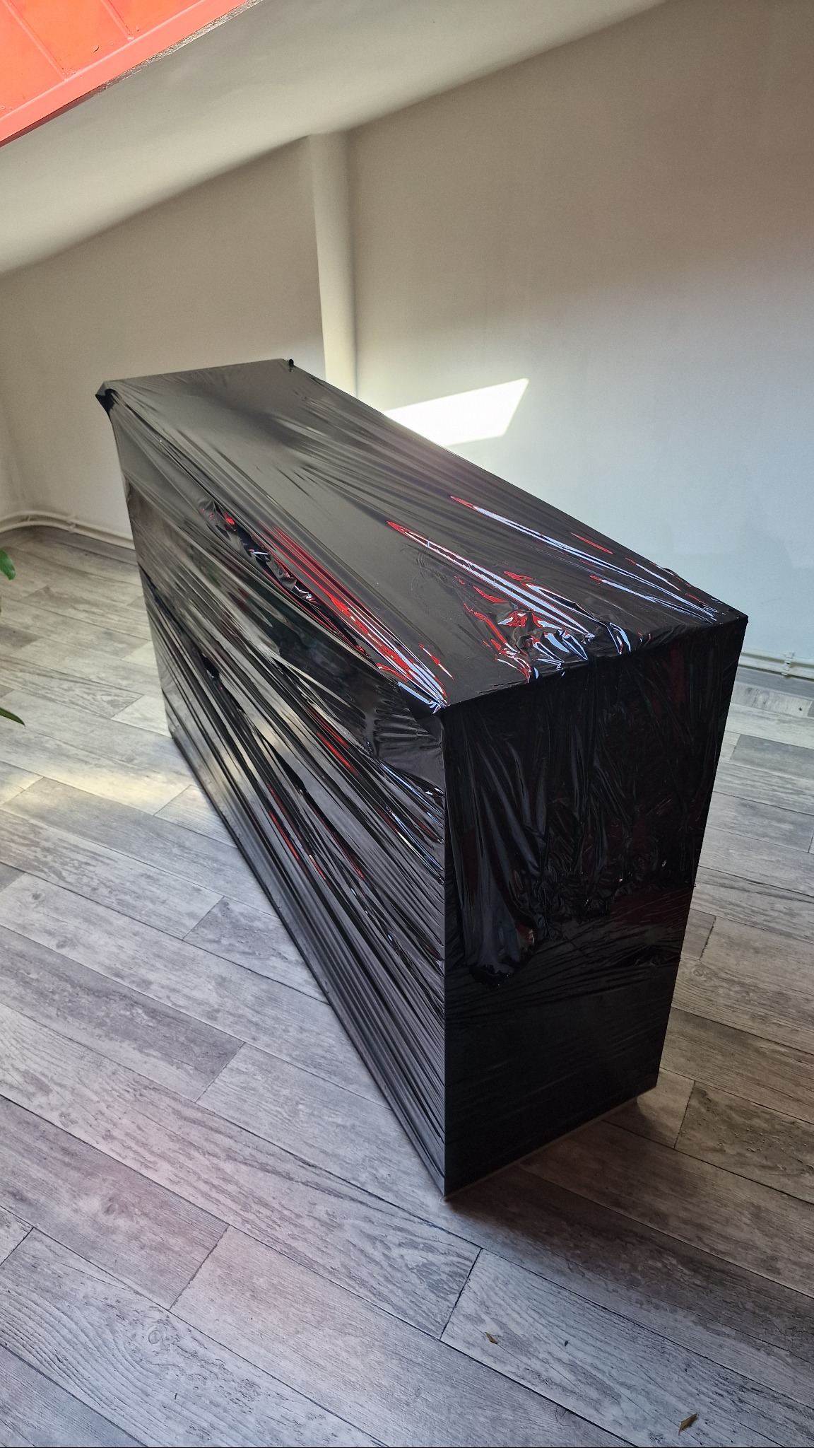 Szafka owinięta czarną folią stretch, przygotowana do transportu. Widoczne zabezpieczenie przed uszkodzeniami w trakcie przeprowadzki.