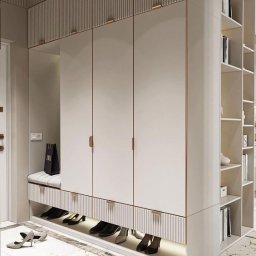 KK-MET Tomasz Kurowski - Biała szafa wnękowa z siedziskiem i półkami na buty, oświetlenie LED u dołu, marmurowa podłoga, torba zakupowa na siedzisku, minimalistyczne uchwyty.