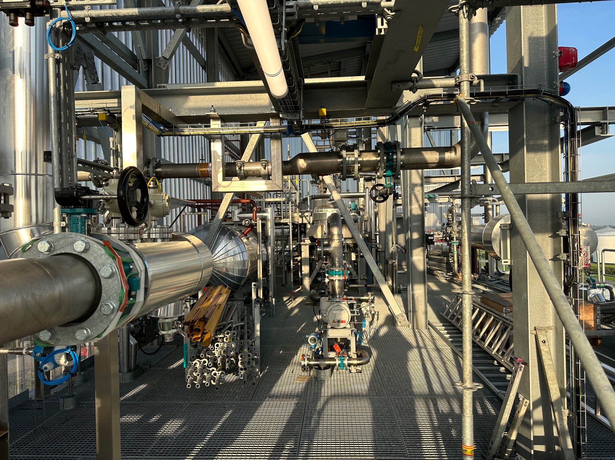 Konstrukcja przemysłowa z rurami, zaworami i metalowymi elementami, widok na skomplikowany system instalacji w jasnym oświetleniu.