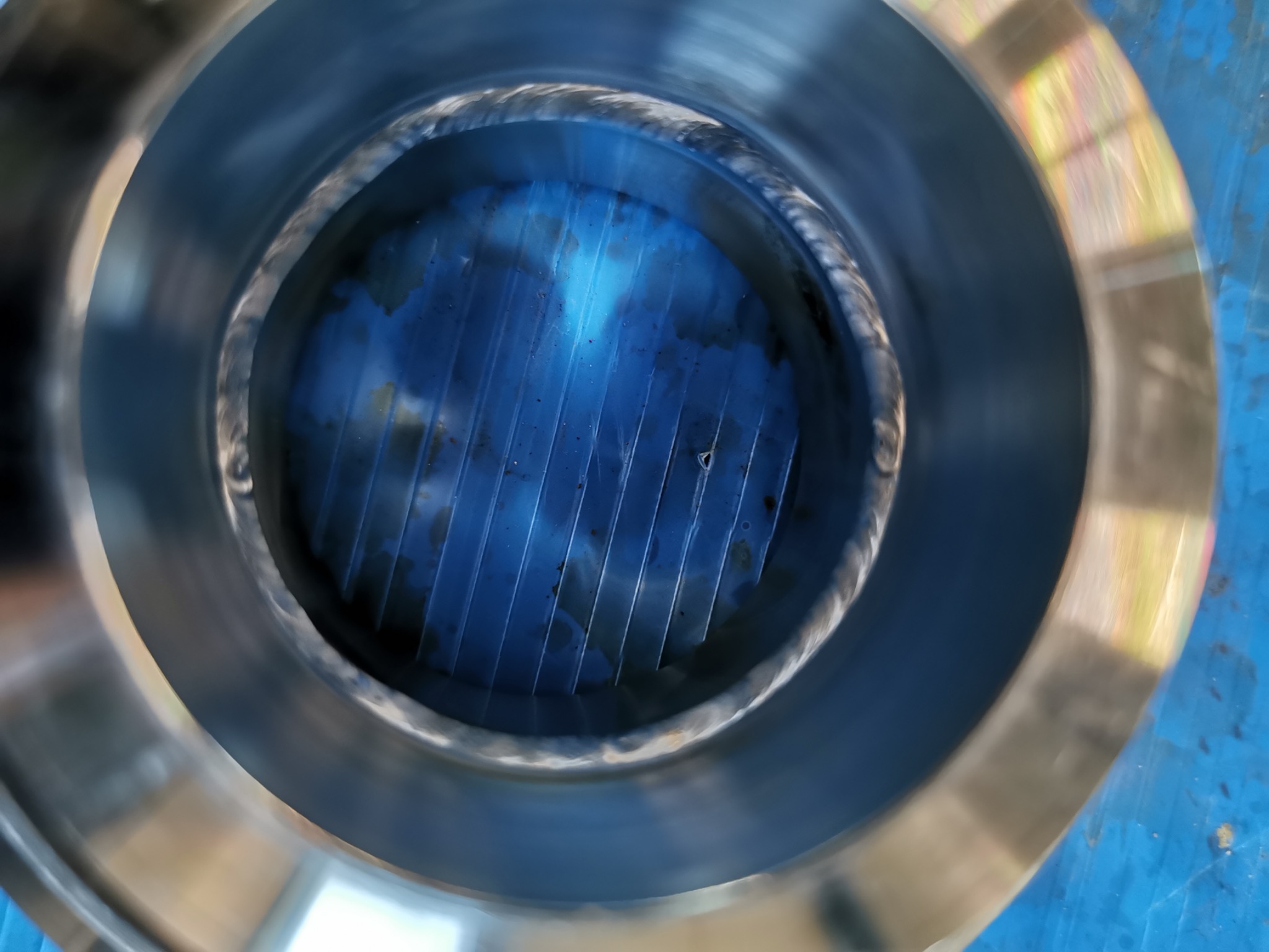 Wnętrze rury z metalu nierdzewnego z widocznymi spawami i niebieskimi elementami konstrukcyjnymi w środku.