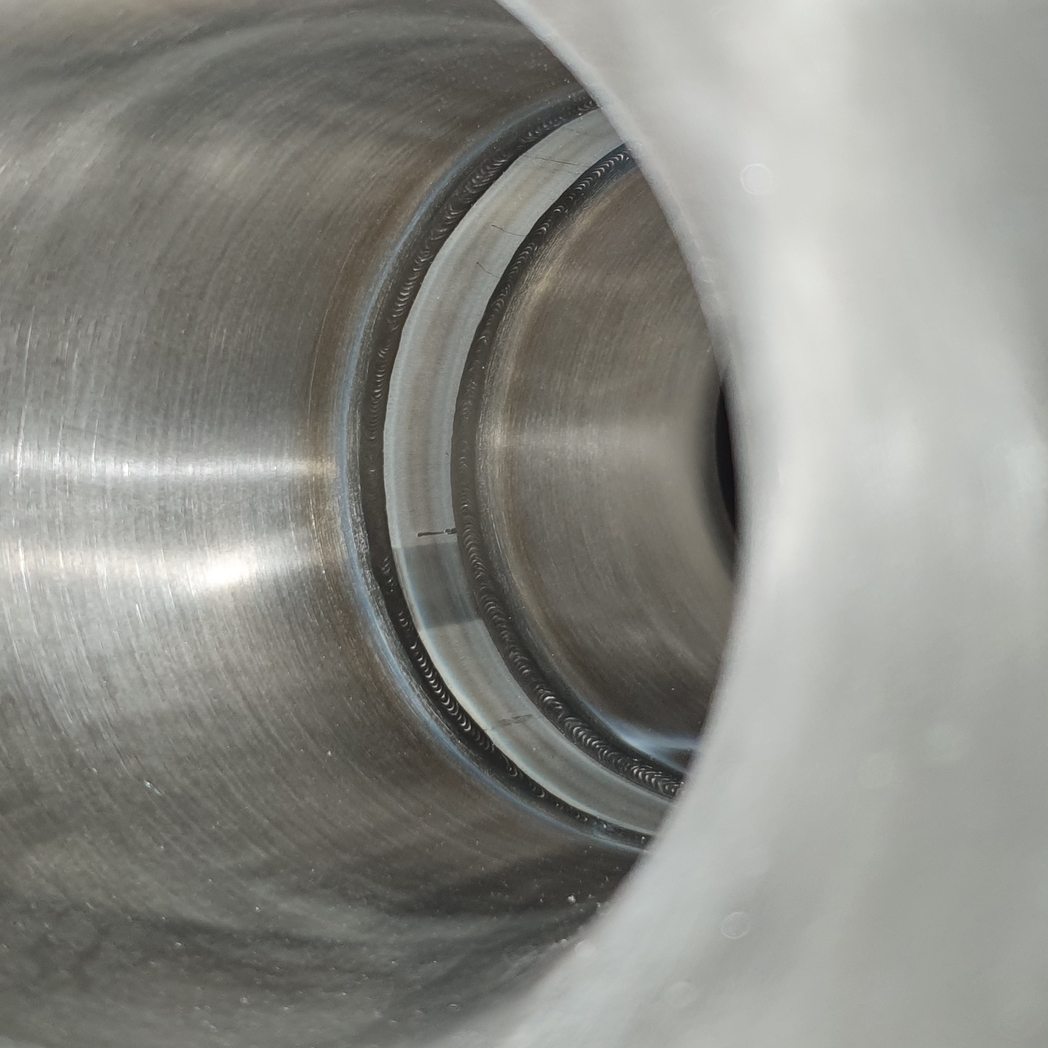 Wnętrze spawanej rury ze stali nierdzewnej, widoczne precyzyjne spawy okrężne z drobnymi śladami po elektrodzie.