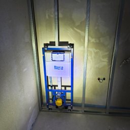 Maj-bud - Stelaż podtynkowy WC marki Roca zamontowany na metalowej konstrukcji przy ścianie w trakcie prac wykończeniowych.