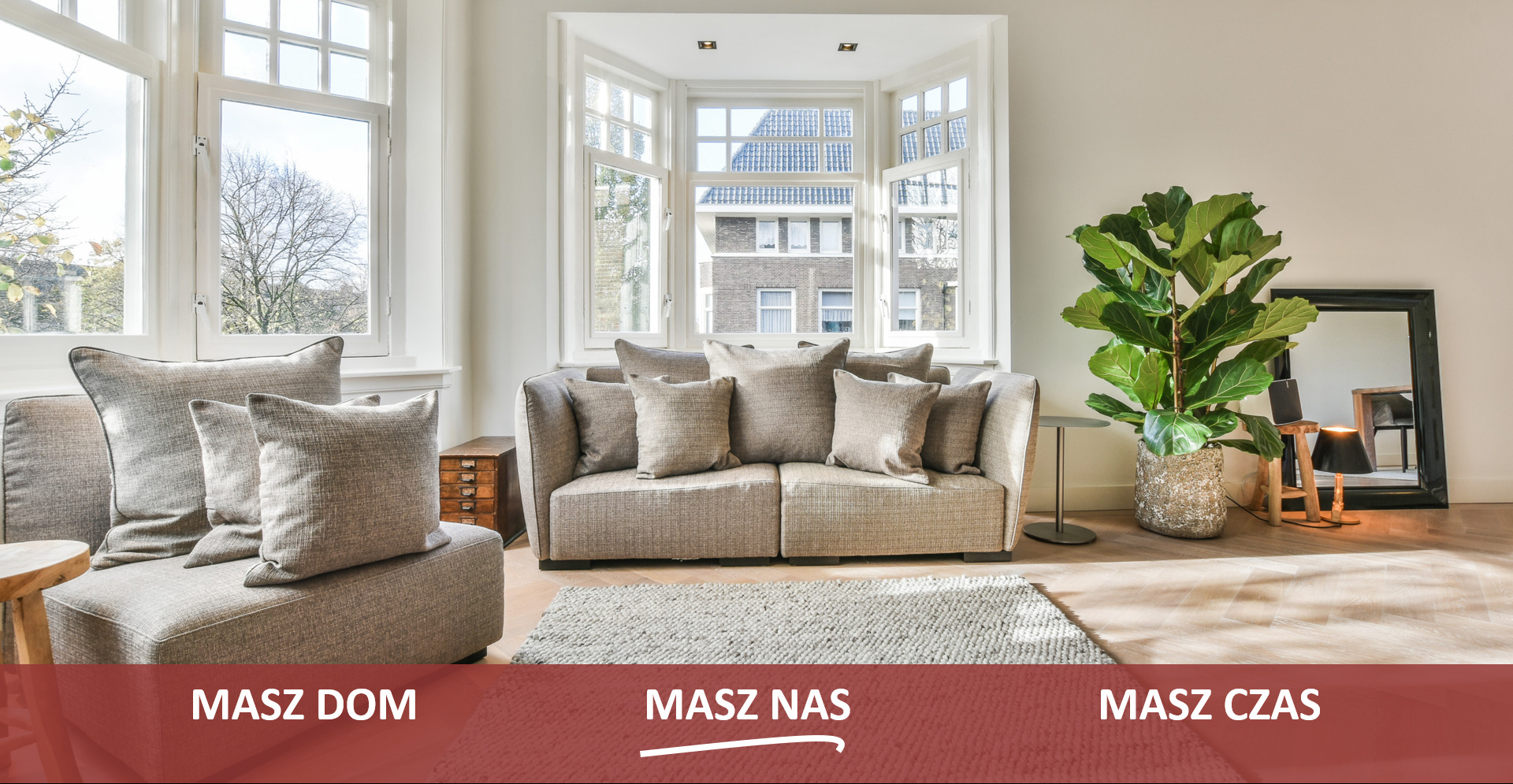 Jasny salon z beżową sofą, poduszkami, fikusiem w ozdobnej donicy, dużym oknem wykuszowym i drewnianą podłogą ułożoną w jodełkę.