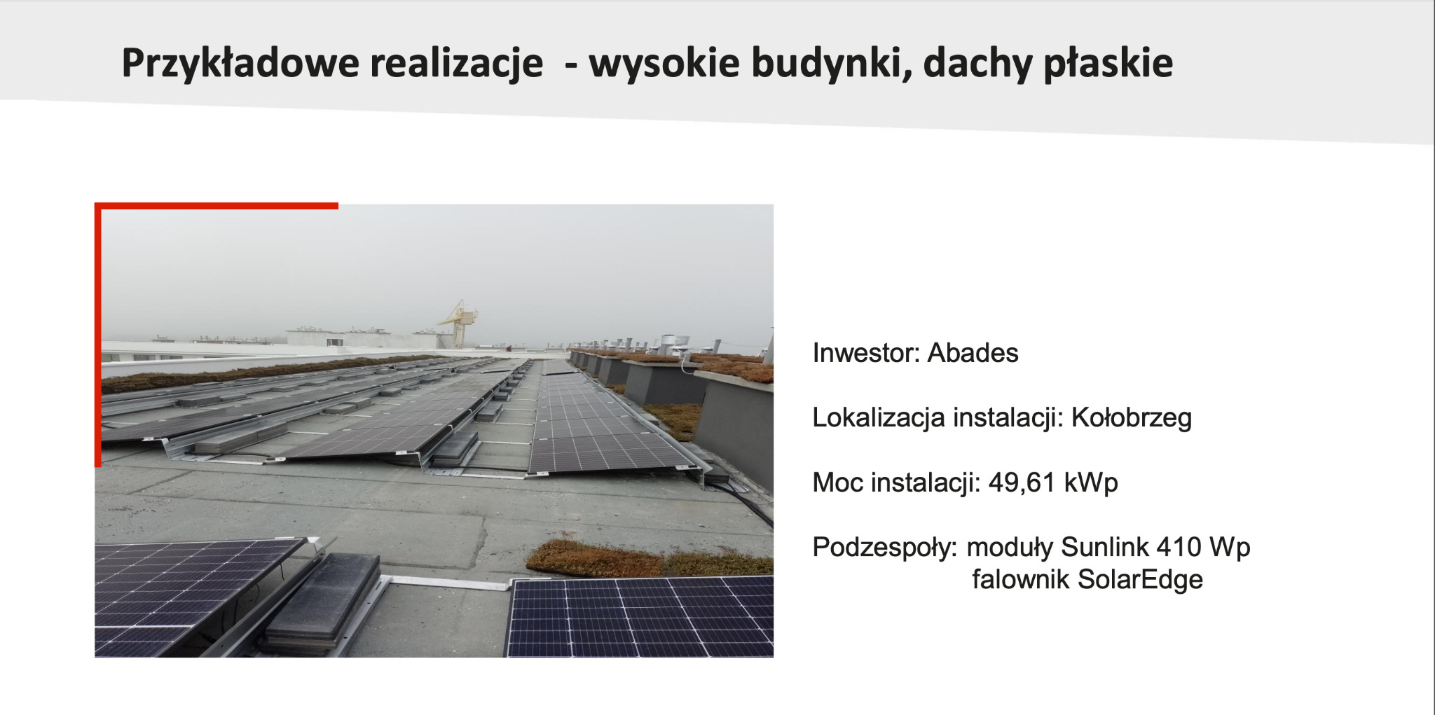 Instalacja paneli słonecznych Sunlink 410 Wp z falownikiem SolarEdge na płaskim dachu wysokiego budynku w Kołobrzegu, inwestor Abades, moc instalacji 49,61 kWp, widok z góry w pochmurny dzień.