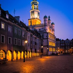 Łukasz Czajkowski - Nocny widok na Stary Rynek w Poznaniu. Oświetlony renesansowy Ratusz z wieżą zegarową góruje nad kolorowymi kamienicami z podcieniami. Puste, wybrukowane plac.