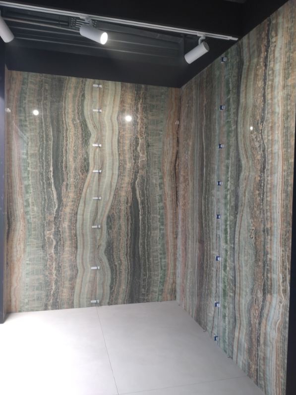 Ściany wykończone panelami z wzorem imitującym agat, zamocowane za pomocą metalowych uchwytów, oświetlenie punktowe na suficie.