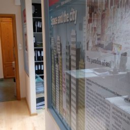 KANCELARIA DORADCY PODATKOWEGO BIURO RACHUNKOWE Paweł Kruszyński - Biuro z regałami na dokumenty; na pierwszym planie ściana z naklejonymi artykułami z gazety The Economist o tematyce ekonomicznej i miejskiej.