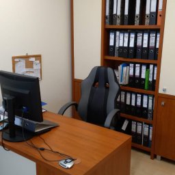 KANCELARIA DORADCY PODATKOWEGO BIURO RACHUNKOWE Paweł Kruszyński - Biuro z biurkiem z drewnianym blatem, krzesłem biurowym w stylu gamingowym i regałem pełnym segregatorów z dokumentami.